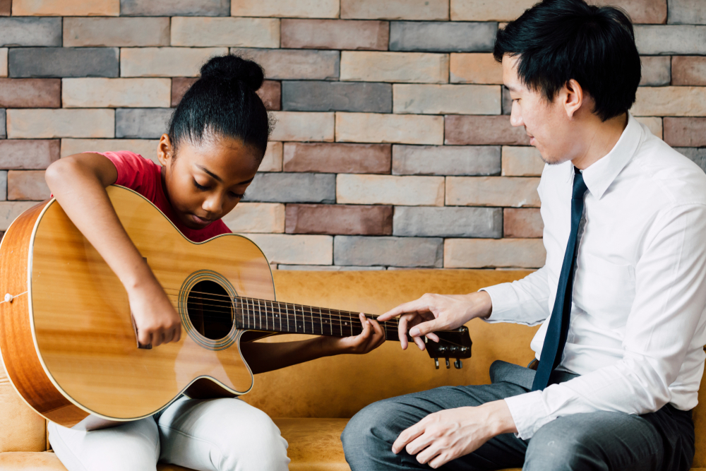 Young Asian male teacher giving a guitar lesson and teaching.