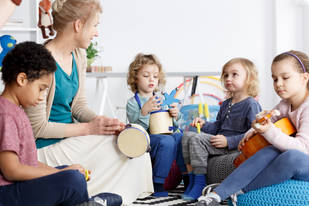 A group of young children explores rhythm and sound with hand instruments during an early childhood music class.
