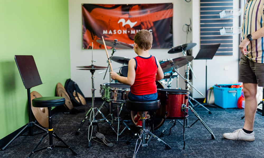 Child playing the drums in Mason Music studio space